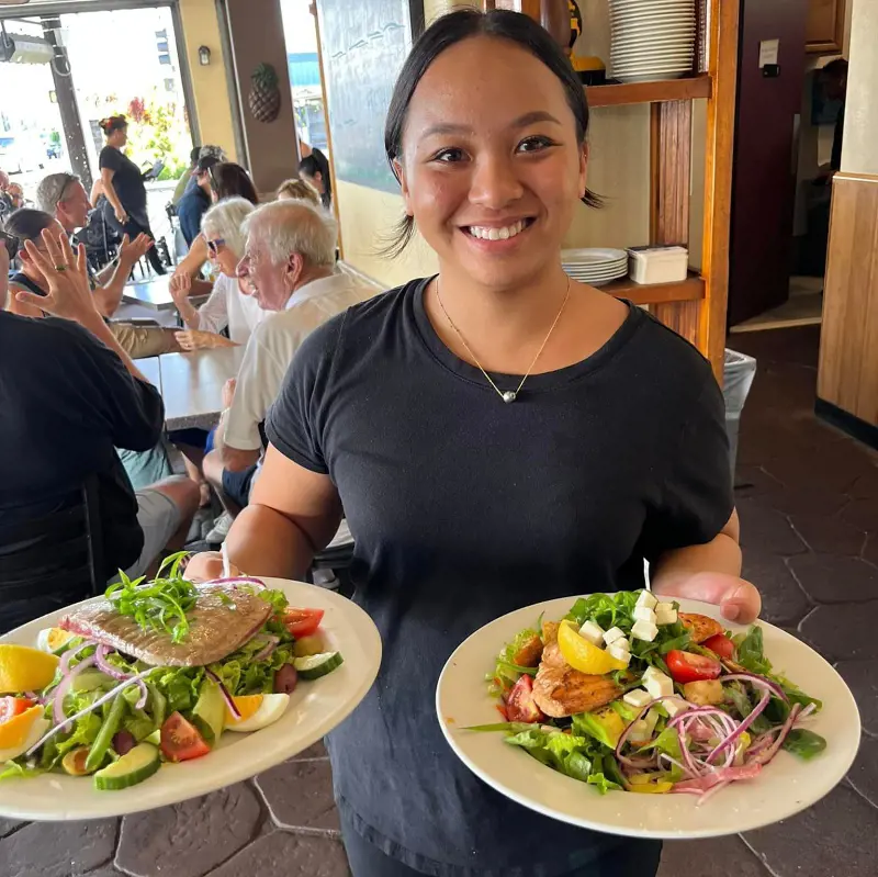 A lady serving freshly made Hawaiian dishes at Pineapples Island Fresh Cuisine