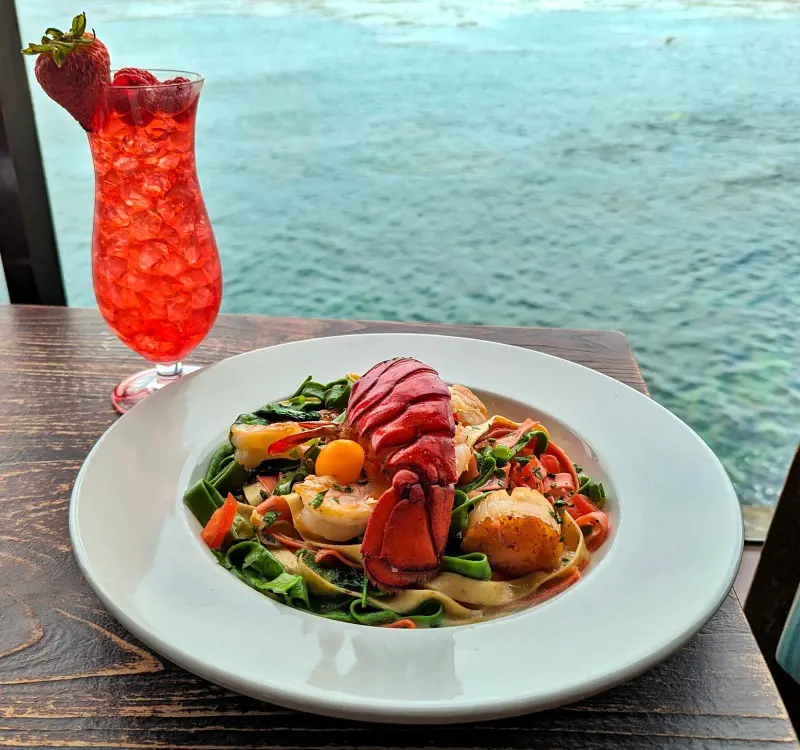 A freshly served seafood item and a cocktail at The Fish Hopper with a panoramic view of the ocean