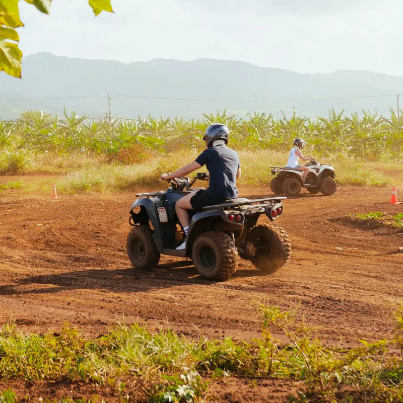 Visitors at North Shore Stables in Oahu enjoying ATV racing on a muddy track