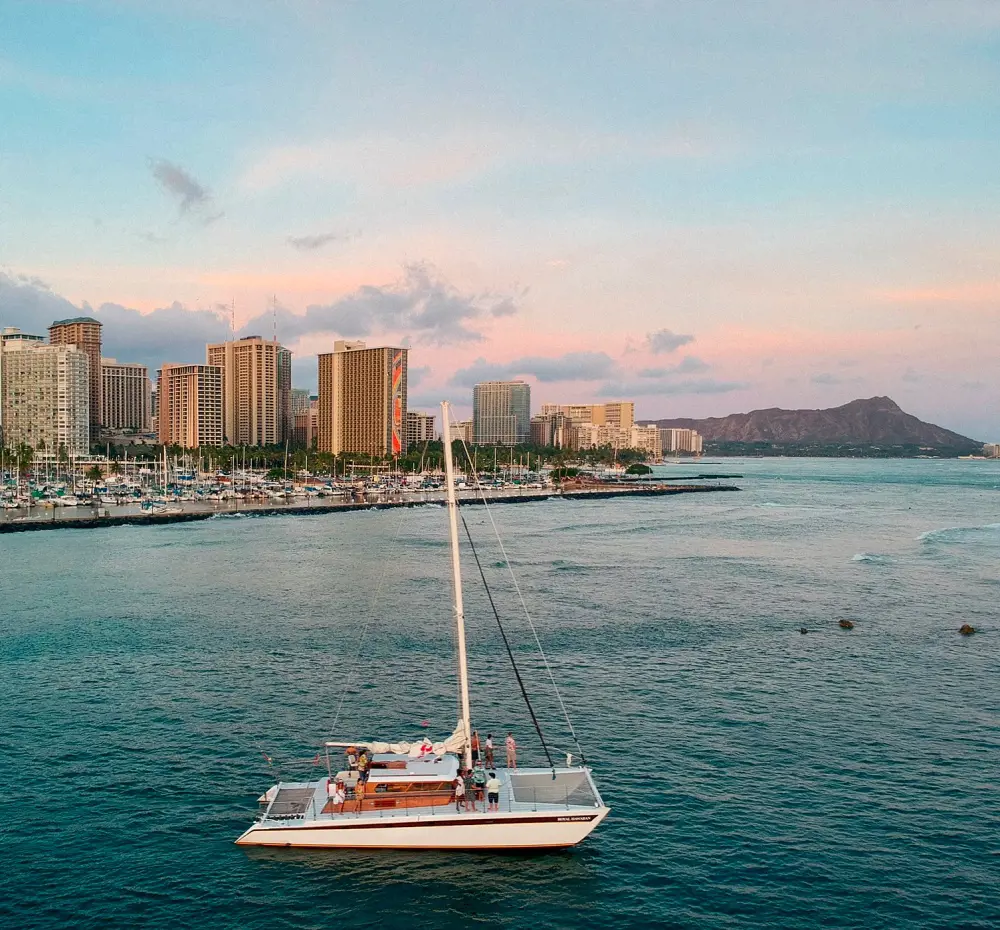 A catamaran sailing in the Hawaiian waters with the scenic Diamond Head on the background